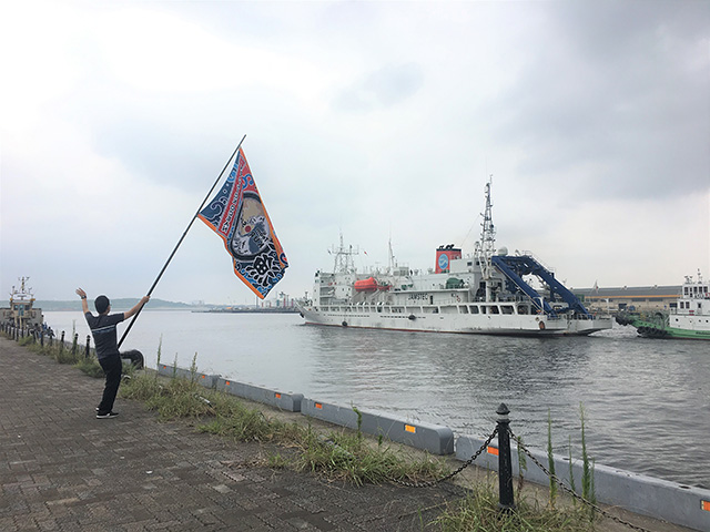 写真：出港時の1シーン。（なぜか）Team KUROSHIOの大漁旗によるお見送り。