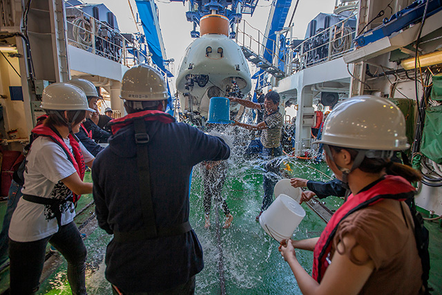 写真：嬉々としてバケツいっぱいの水をかける宮崎氏（中央）。この水かけは「しんかい6500」初潜航を祝う（？）恒例儀式である。