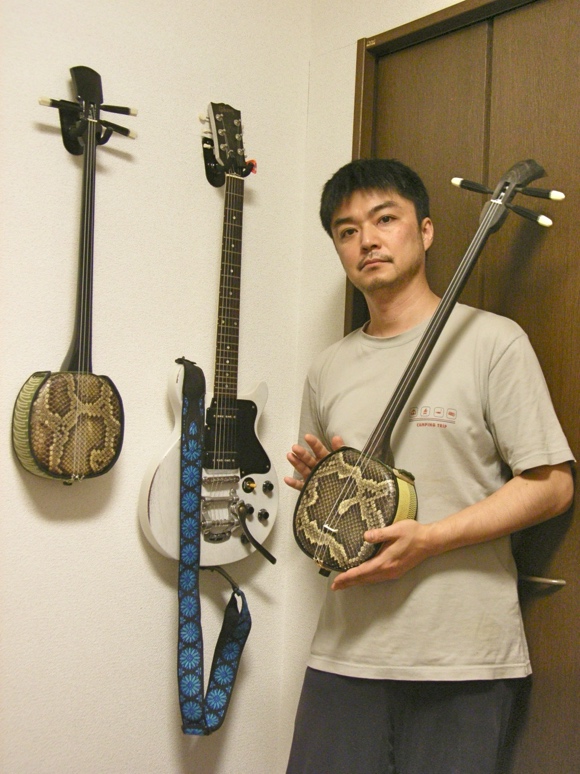 写真：三線とギターの前の生田さん