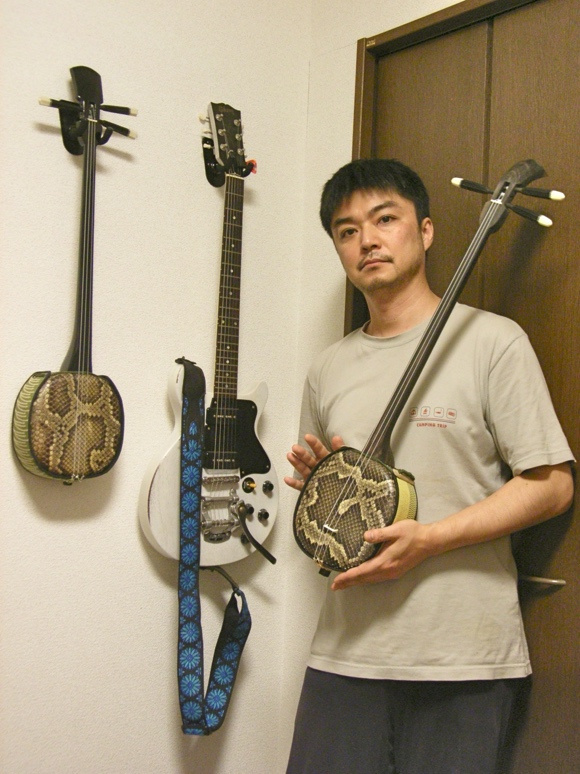写真:三線とギターの前の生田さん