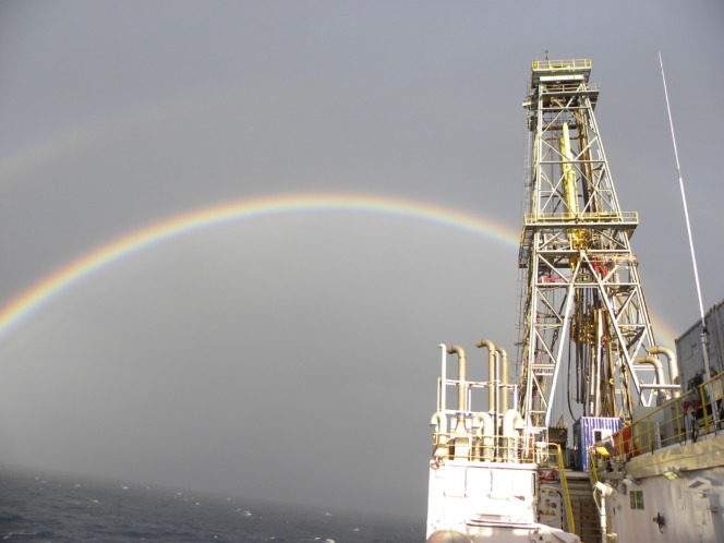 掘削船ジョイデスレゾリューション号の掘削やぐら越しに虹がかかっている写真